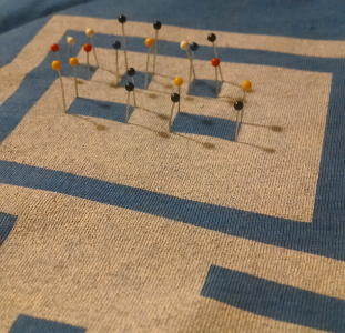 Straight pins stuck through the shirt at the intersections of each block representing the cursor text on the shirt design