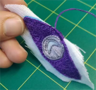 Beginning to work a looped outline element around the freed edges of the design, now freed from the hoop and the larger linen swatch.