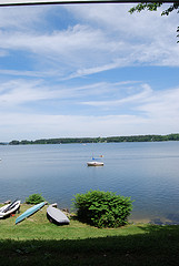 An unrigged sailboat in a lake on a sunny day.