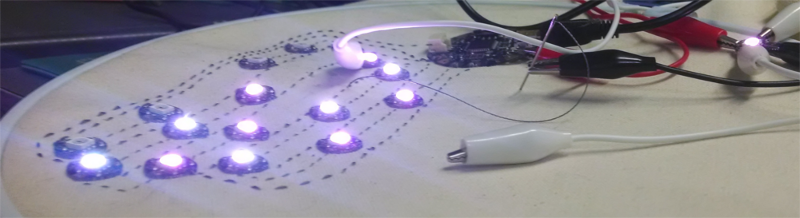 The 18-LED circuit with populated data lines. Approximately half the LEDs are dark, and two LEDs are plumbed into the circuit with alligator clips for testing.