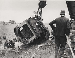 A train car is on its side, with a crane hoisting it back into place